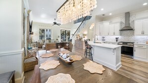 A spacious kitchen with a central island, white cabinetry, and a modern chandelier. - Jules in the Sand | Renovated Gulf-Front Escape (Panama City Beach)