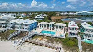 A beachfront property with multiple houses, a swimming pool, and a dock. - Jules in the Sand | Renovated Gulf-Front Escape (Panama City Beach)