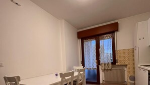 Ein Essbereich mit Tisch und Stühlen, einem Heizkörper und einem Fenster mit Vorhängen.