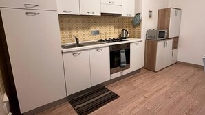 Eine moderne Küche mit weißen Schränken, einem Gasherd, einer Mikrowelle und einem Kühlschrank.