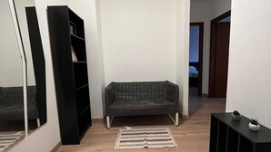 Ein Wohnzimmer mit einer Couch, einer schwarzen Unterhaltungsecke und einem Spiegel.