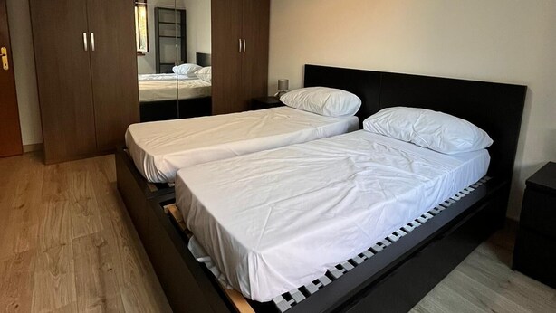 Ein modernes Schlafzimmer mit einem großen Bett, Holzböden und einem Schrank mit Schiebetüren.