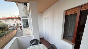 Ein Balkon mit Tisch und Stühlen, ein Fenster und Blick auf die Straße.