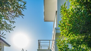 A staircase leading to a balcony with a railing, surrounded by greenery and a clear sky. - KAYA APARTMENTS KALAMAR (Kas)