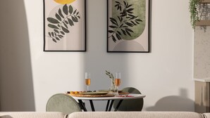 A modern living room with a beige sofa, two framed artworks, a small table with drinks, and a hanging plant. - KAYA APARTMENTS KALAMAR (Kas)