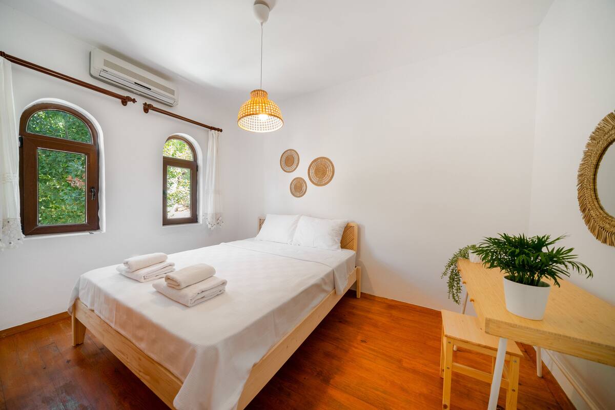 A bedroom with a bed, a wooden bench, a potted plant, and two wall-mounted circular decorations.