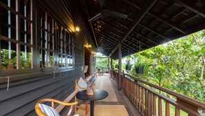 A covered outdoor area with wooden railings, a table, and chairs. - Atoh's Maison (Siem Reap)