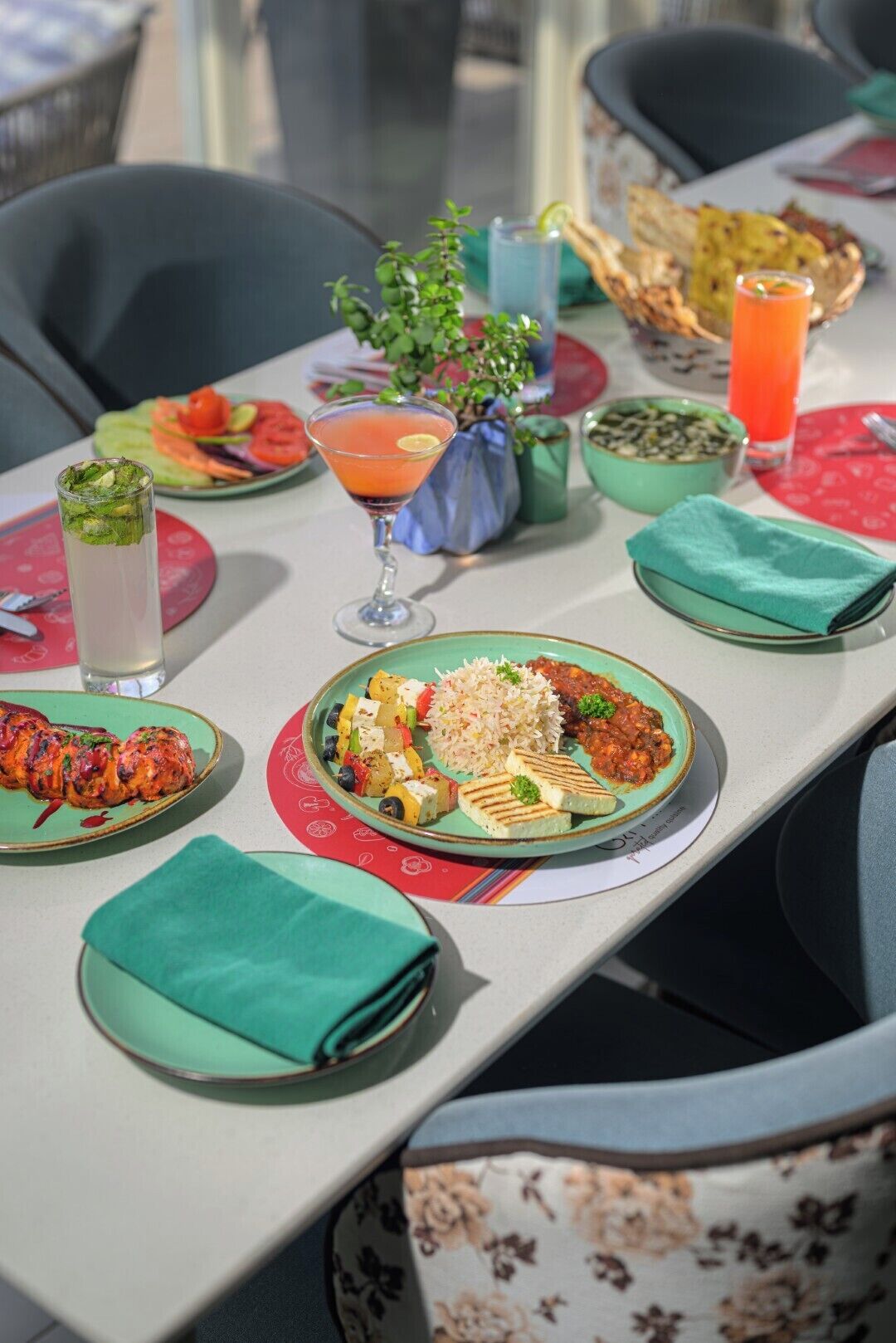 A table set with various dishes, drinks, and a small plant.