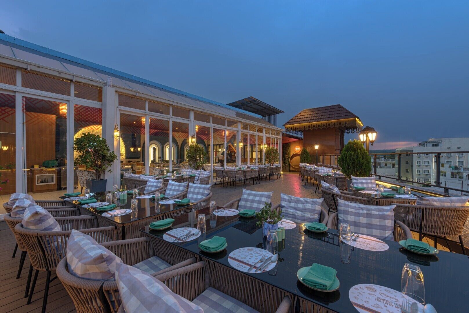 An outdoor dining area with wicker furniture, glass tables, and potted plants.