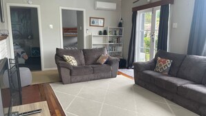 Una sala de estar con dos sofás, una estantería y un televisor.