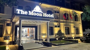 Hotel Moon, con una entrada destacada, fachada bien iluminada y exhibición de banderas.