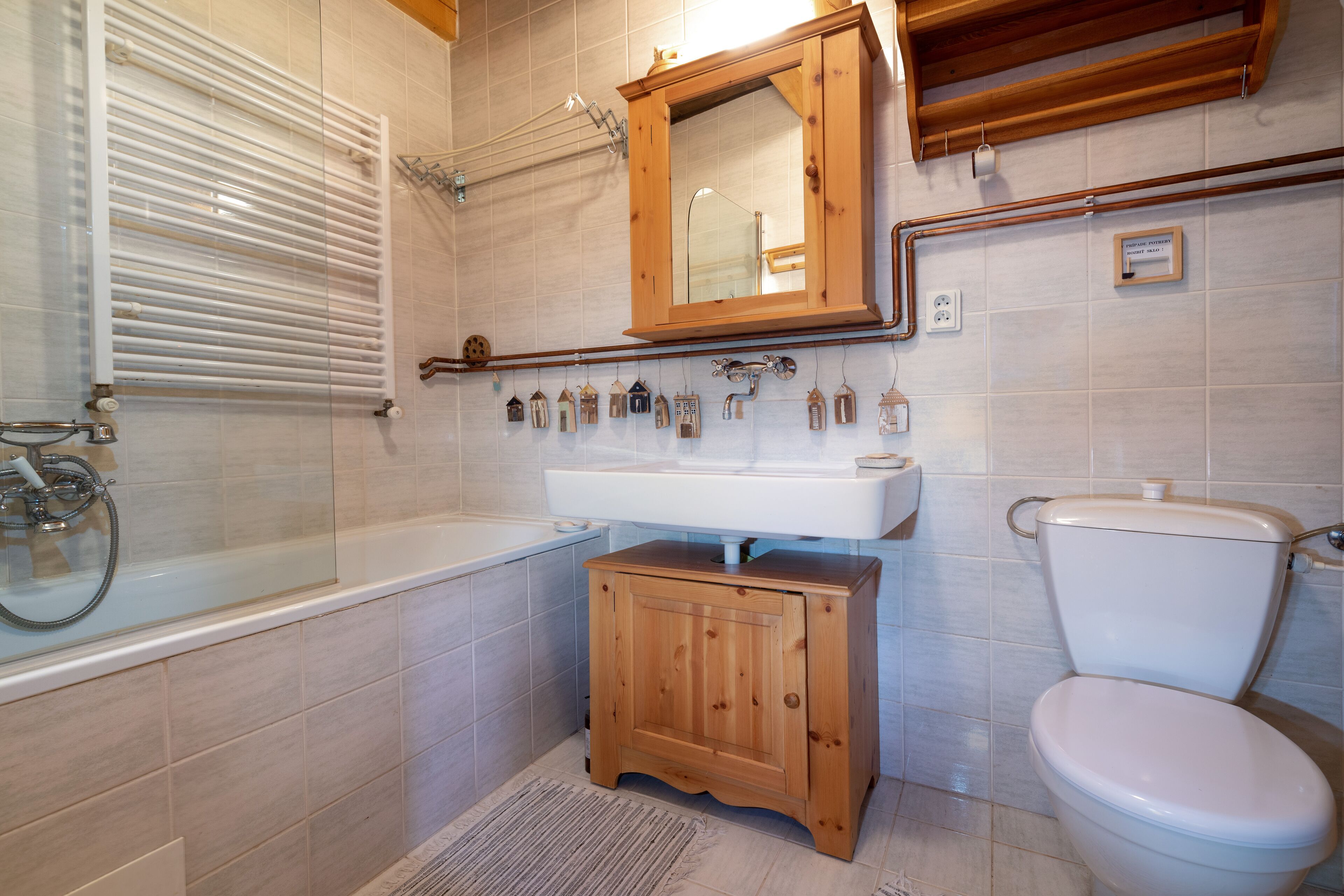 Un bany amb banyera, un armari de fusta, un lavabo i un vàter.