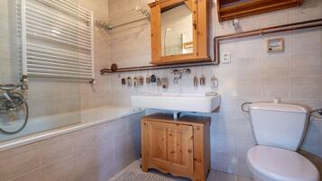 Un bany amb banyera, un armari de fusta, un lavabo i un vàter.
