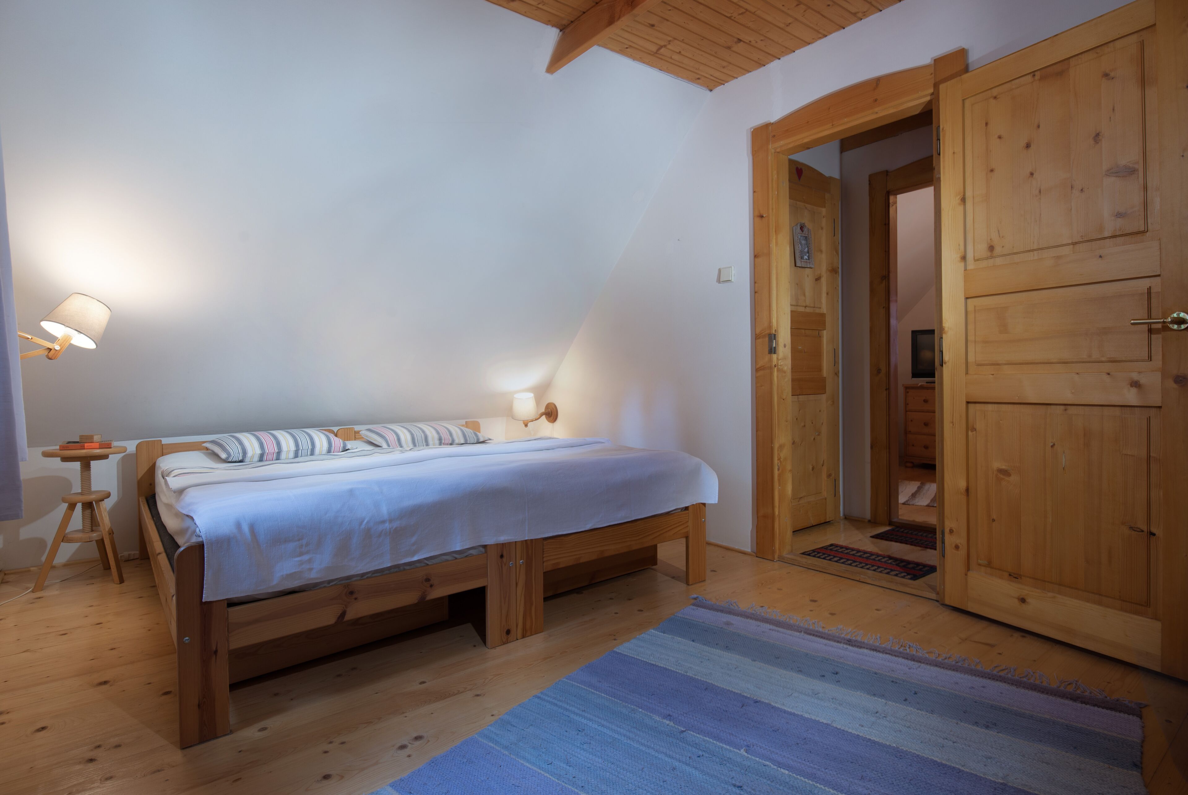 Un dormitorio con una cama de madera, una mesita de noche, una lámpara y un armario.