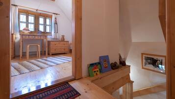 Una camera accogliente con pavimento in legno, una panca, un tavolino con una lampada e una finestra con tende.