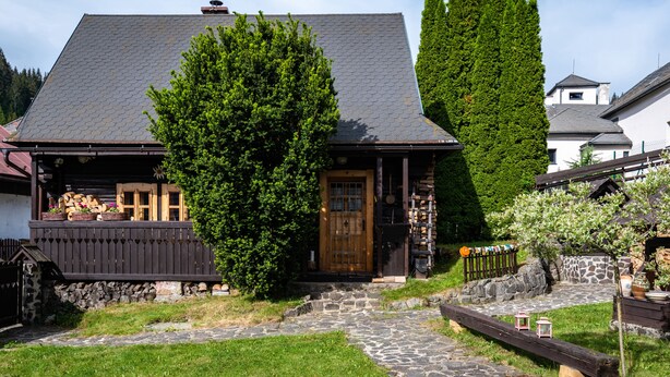 Een klassiek chalet met een gevel van natuursteen, houten luiken en een pad van stenen dat naar de ingang leidt.