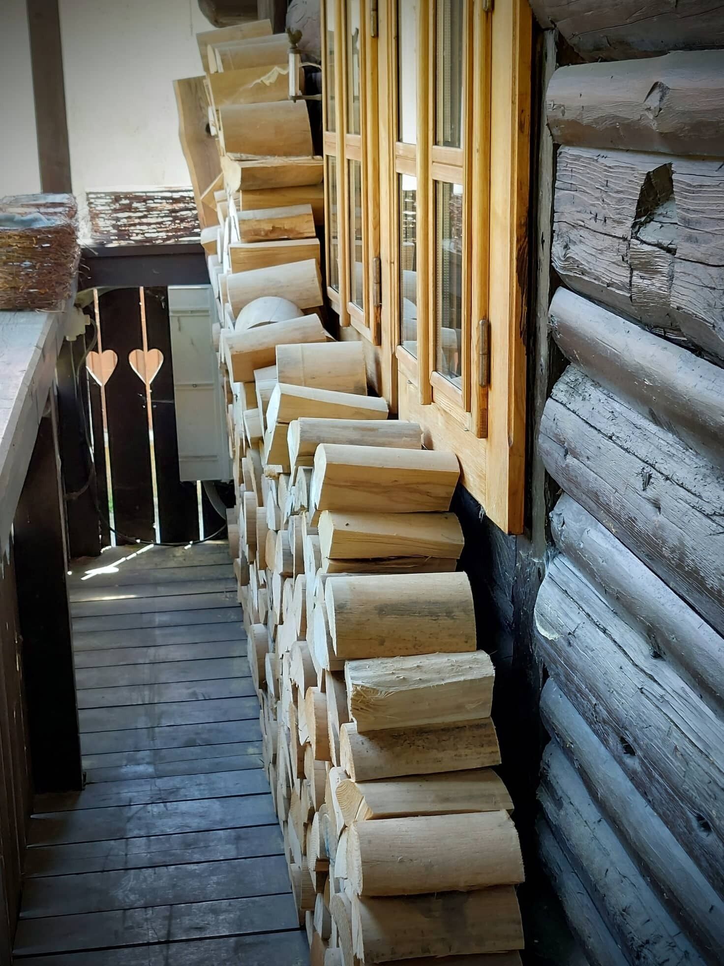 A narrow hallway with wooden logs stacked against the walls and a wooden bench along the left side.