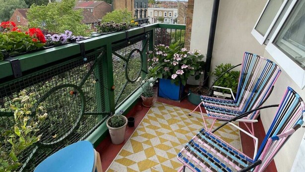 A balcony with a yellow and white checkered floor, two blue chairs, and potted plants. - Contemporary 1BD Flat W/balcony - Stoke Newington! (London)