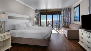 Quarto de hotel com uma cama grande, televisão, cômoda e varanda com vista para o mar.