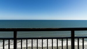 Het uitzicht op de oceaan vanaf een balkon met een balustrade.