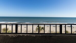 A beach view from a balcony with a railing, sandy beach, and ocean. - Newly Renovated 4th Floor Oceanfront Efficiency (Myrtle Beach)