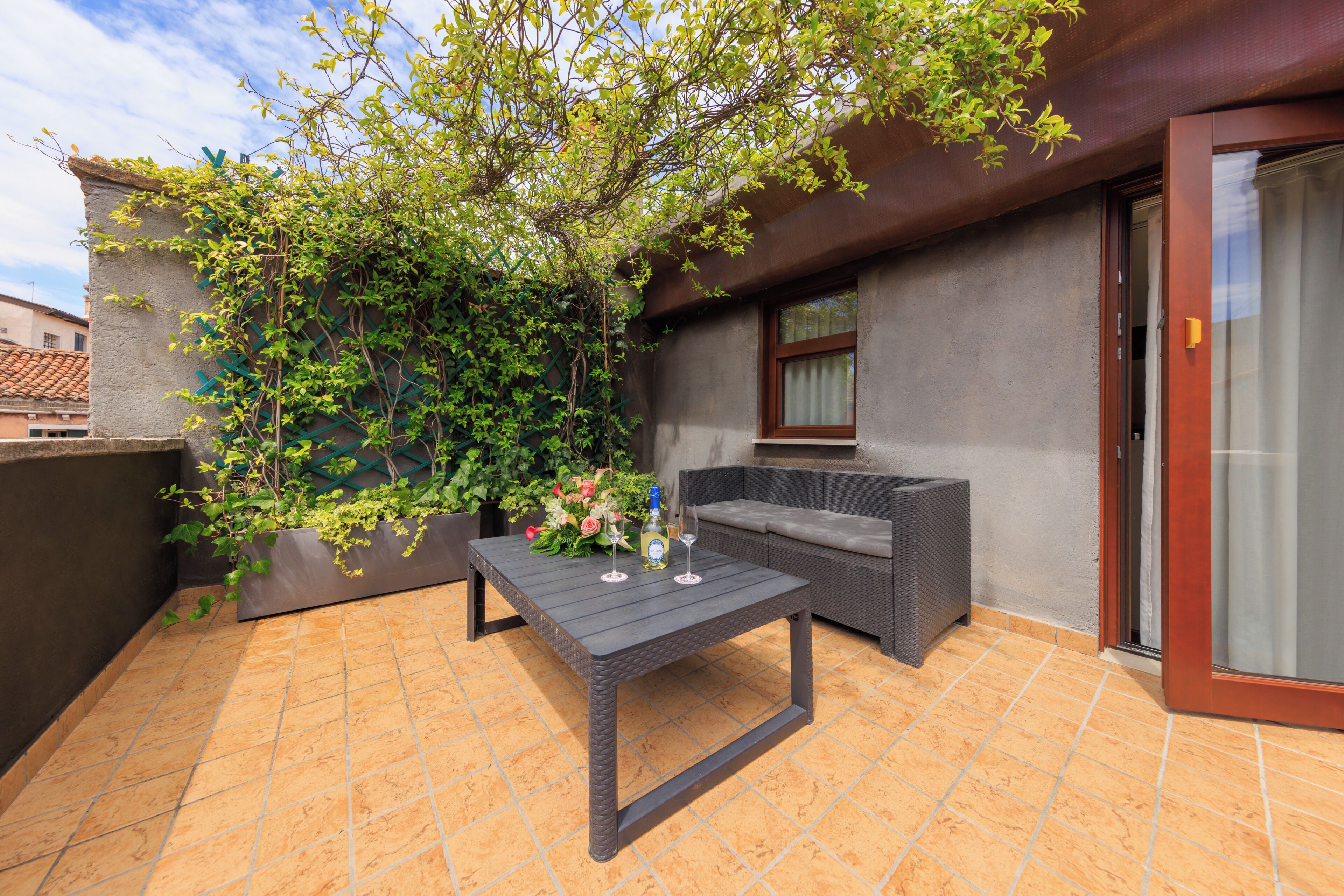 A patio with a table, a sofa, and a potted plant.