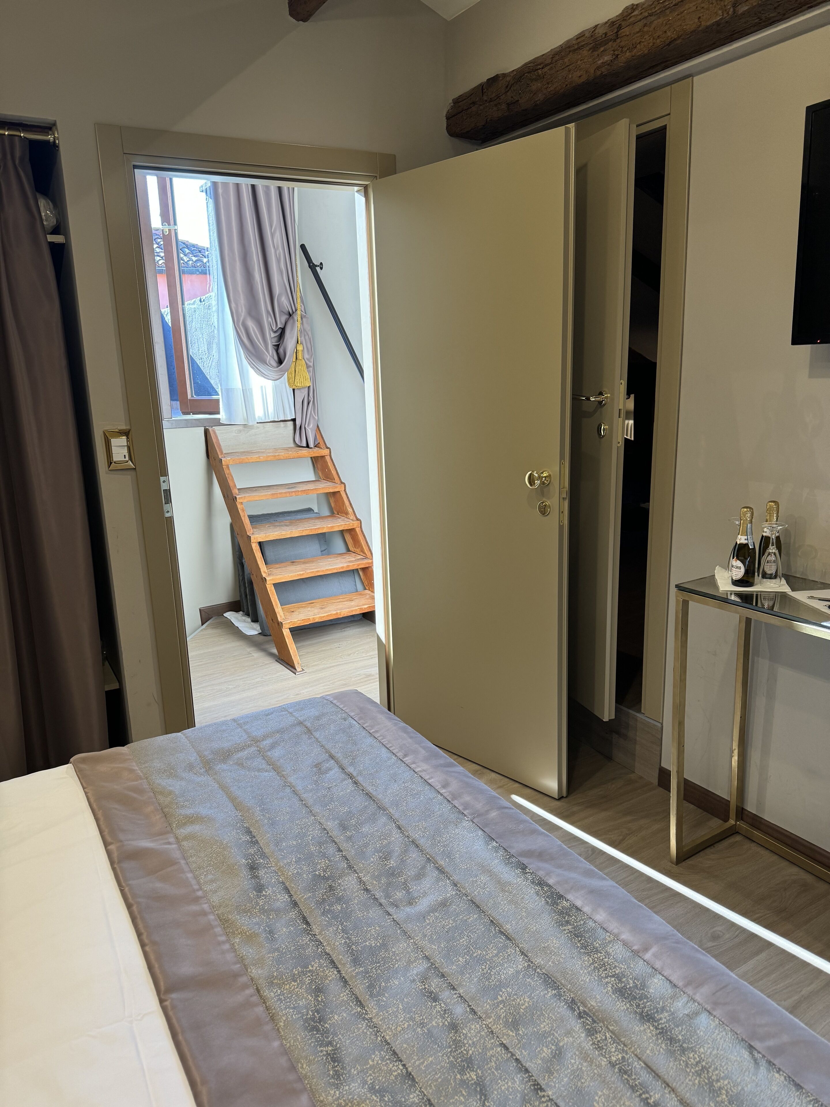 Ein Schlafzimmer mit einem Bett, einer Holztreppe, einem Kleiderschrank und einem kleinen Tisch mit Flaschen.