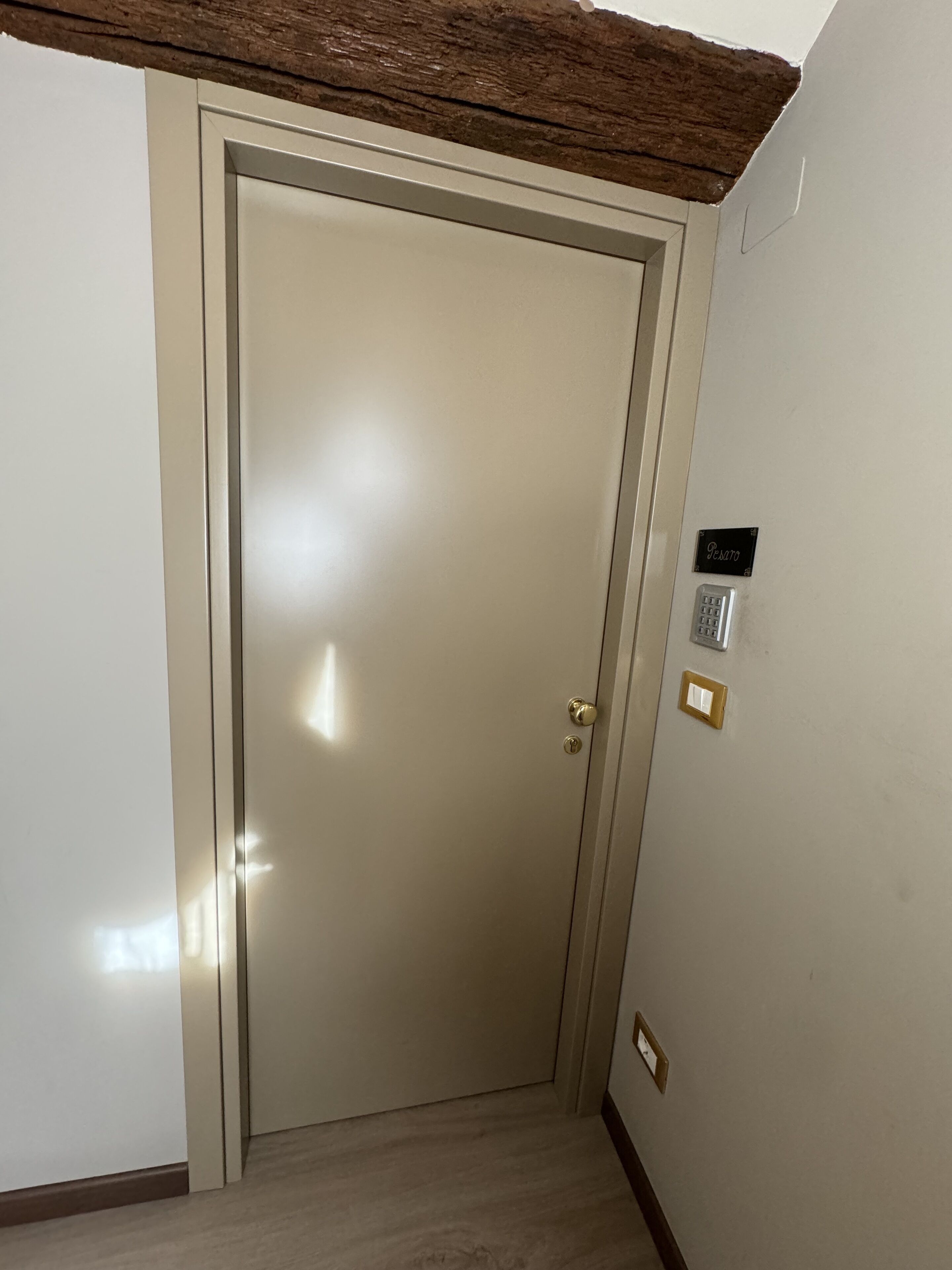 Una puerta cerrada con un teclado de bloqueo y un interruptor de luz en la pared.