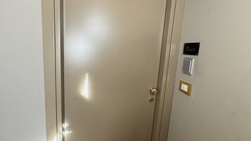 Una puerta cerrada con un teclado de bloqueo y un interruptor de luz en la pared.