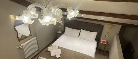 A bedroom with a large bed, a chandelier, a bedside table, and a radiator.