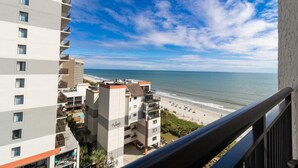 A high-rise hotel with multiple balconies overlooking a beach.