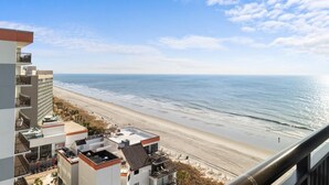 Un edificio alto con vista a una playa, con una vista despejada del océano y una orilla de arena.