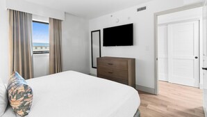 Una habitación de hotel con cama, cómoda, televisor y puerta.