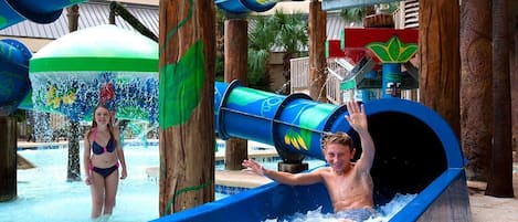 A water slide with a person sliding down and another standing nearby.