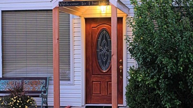 A wooden door with a decorative glass panel and a sign above it that reads "Welcome to the Lake."