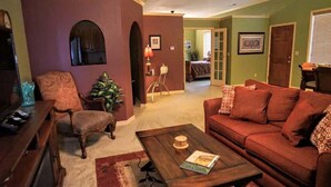 A living room with a red sofa, a wooden coffee table, and a patterned armchair.