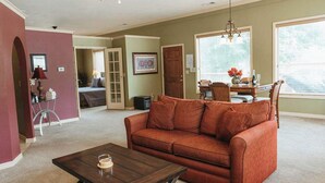 A living room with a brown sofa, a coffee table, and a dining area with a table and chairs.