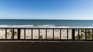 Blick auf einen Strand vom Balkon mit Geländer, Sandstrand und Meer.