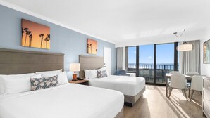 Ein Hotelzimmer mit zwei Betten, einem Schreibtisch, Stühlen und einem Balkon mit Blick.