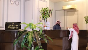 A reception desk with a sign reading "Reception" and two clocks displaying times for Makkah and London. - Maysan Al Mashaer Hotel (Makkah)