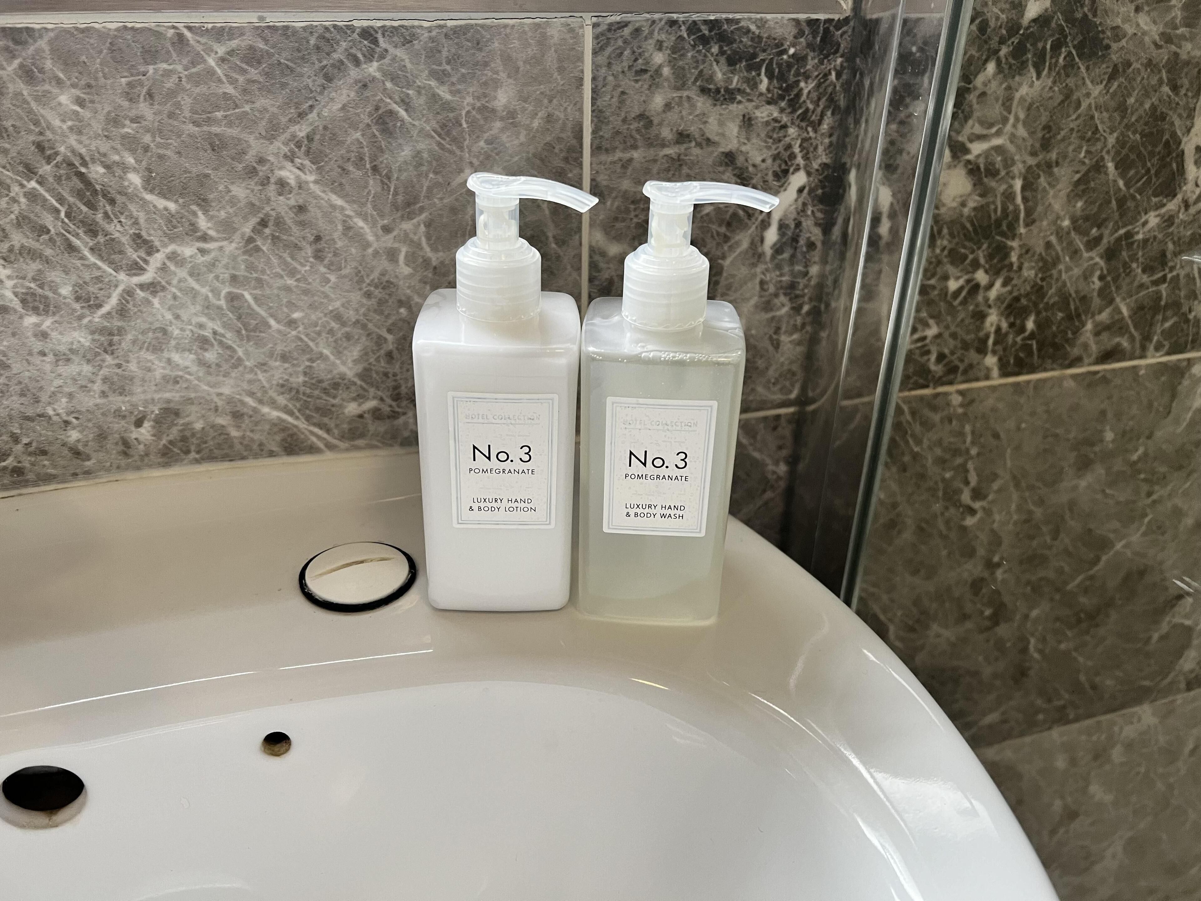 Due flaconi di crema e detergente corpo e mani No. 3 Pomegranate Luxury, su un lavabo da bagno.