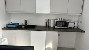 Une cuisine compacte équipée d’un évier, d’un four à micro-ondes et d’un grille-pain.