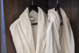 Een houten garderobe met twee witte handdoeken aan zwarte ophangers.