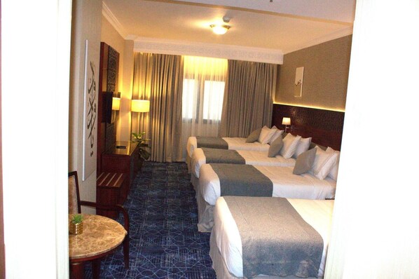 Una habitación de hotel con una cama grande, una cama más pequeña, un escritorio y una silla.