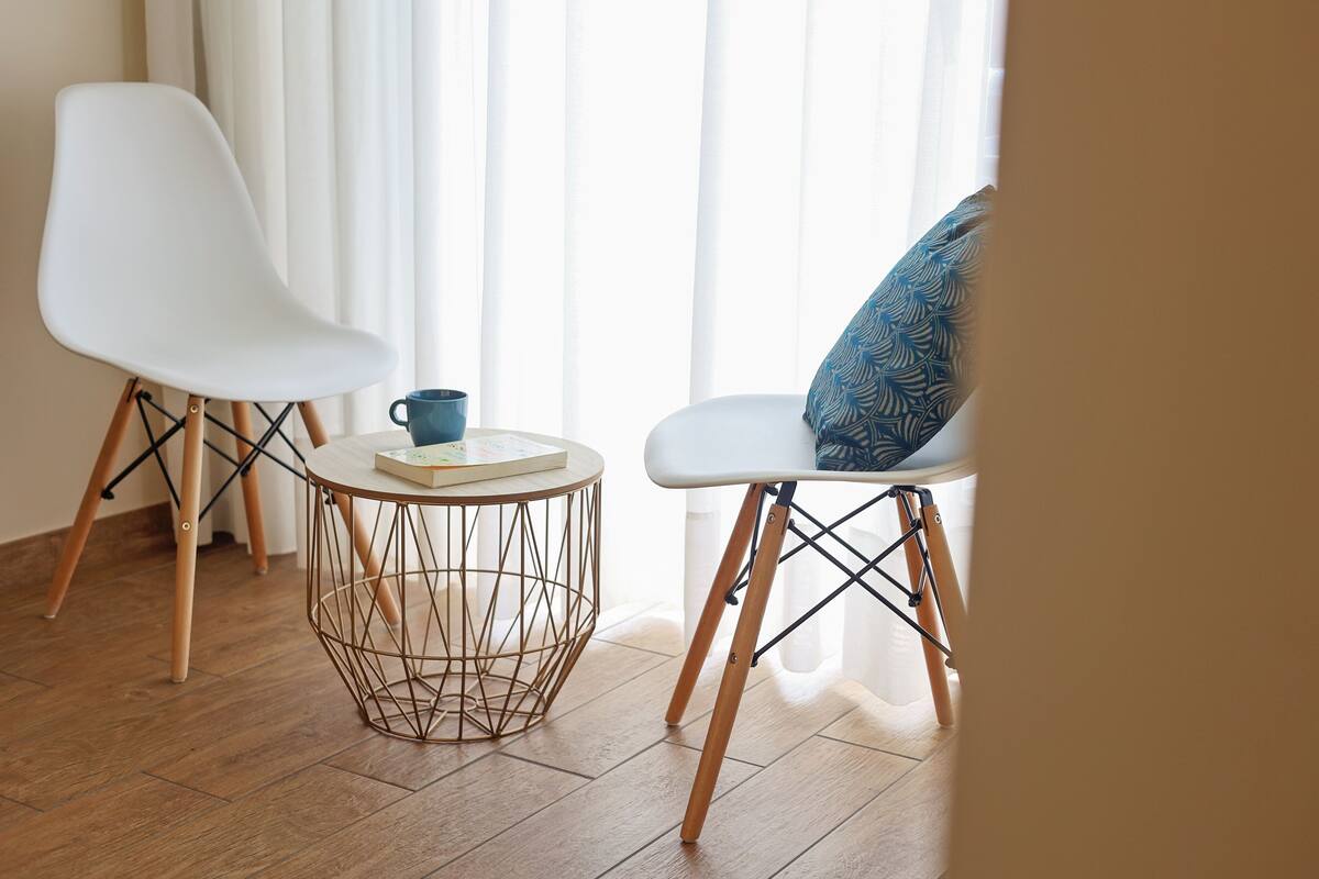 A modern room with two white chairs, a round coffee table, and a patterned pillow.