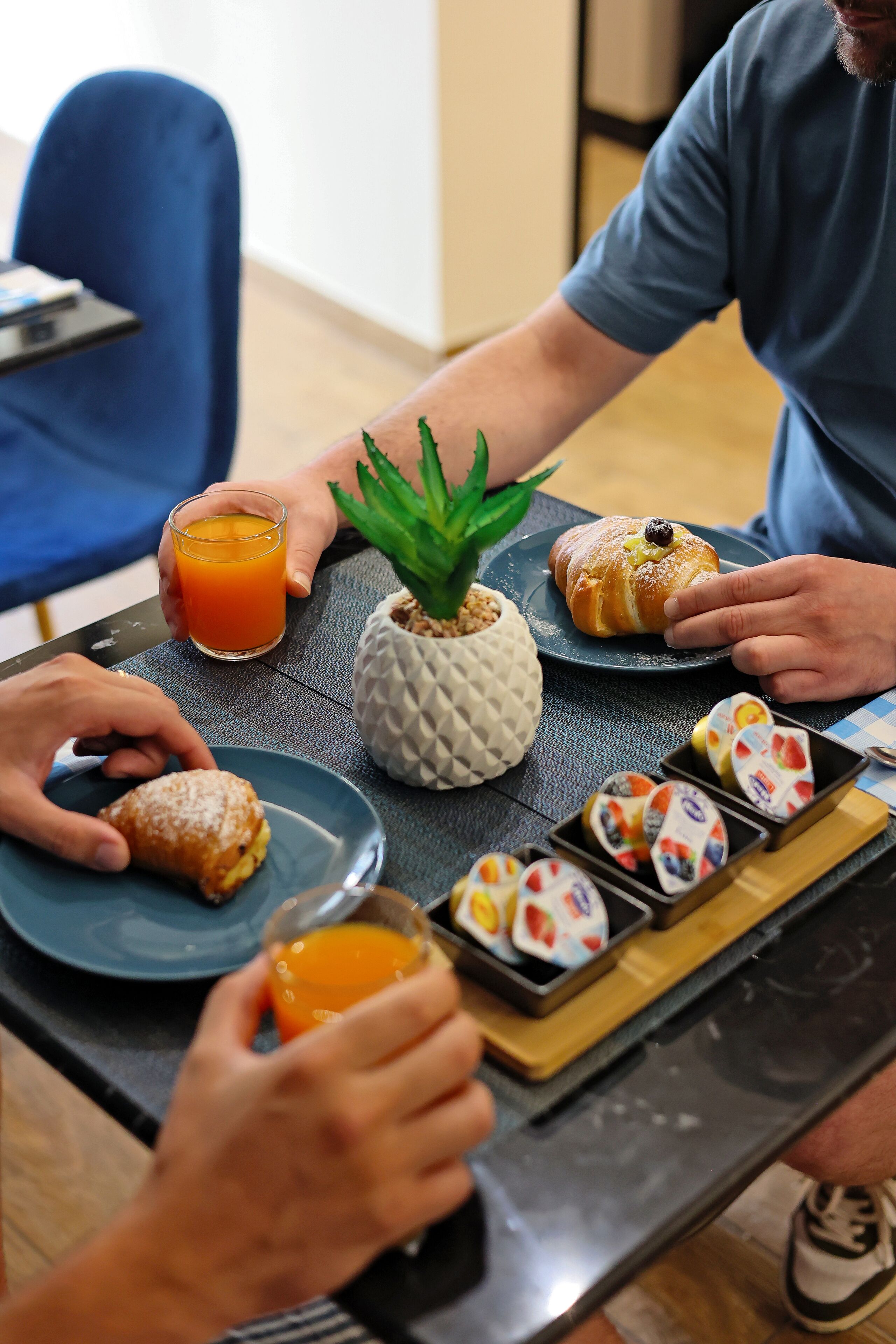 Uma mesa de jantar com uma aranha de abacaxi, um croissant e um copo de sumo de laranja.