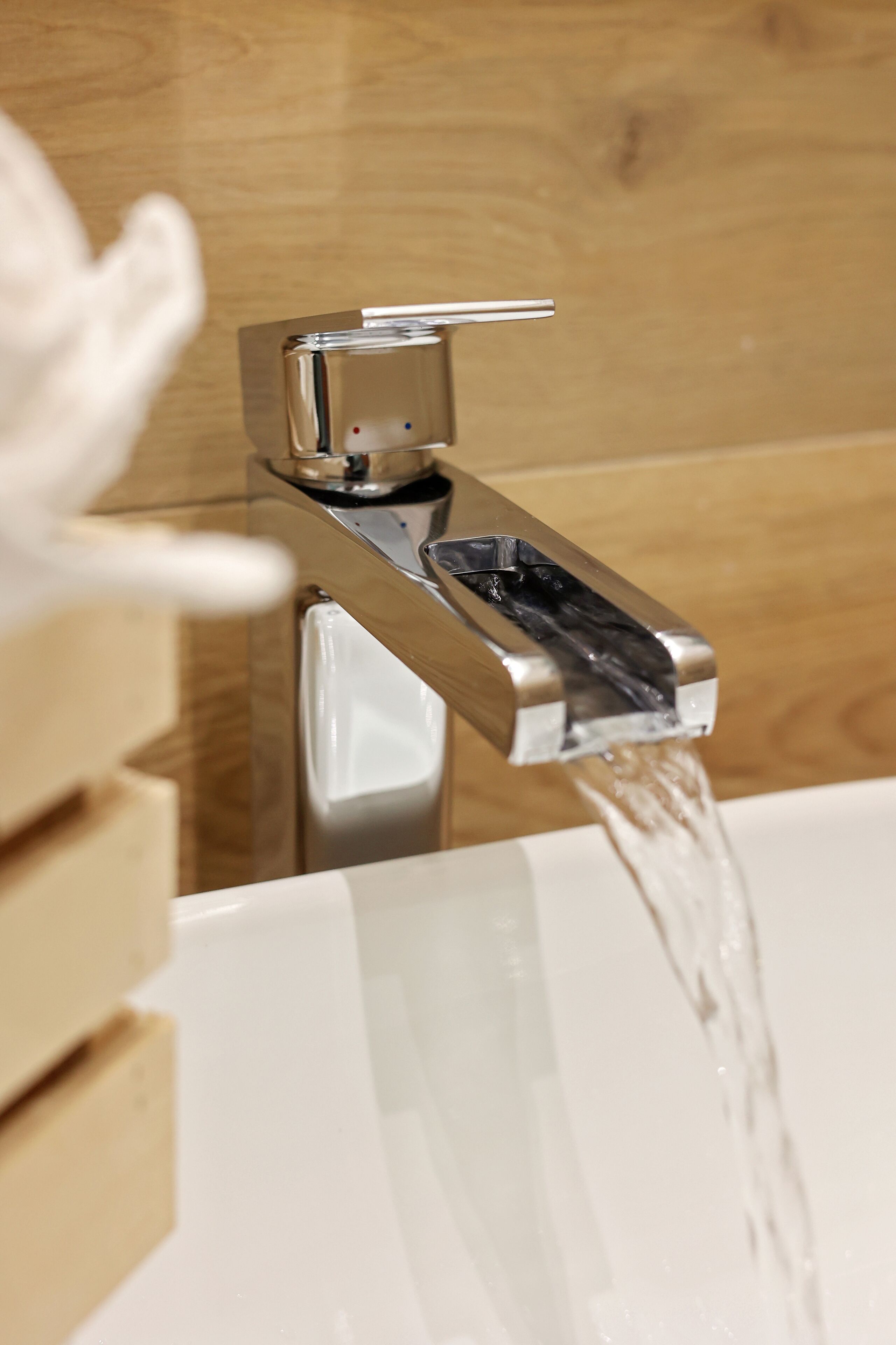 A modern bathroom with a chrome faucet and a clear view of water flowing into a white bathtub.