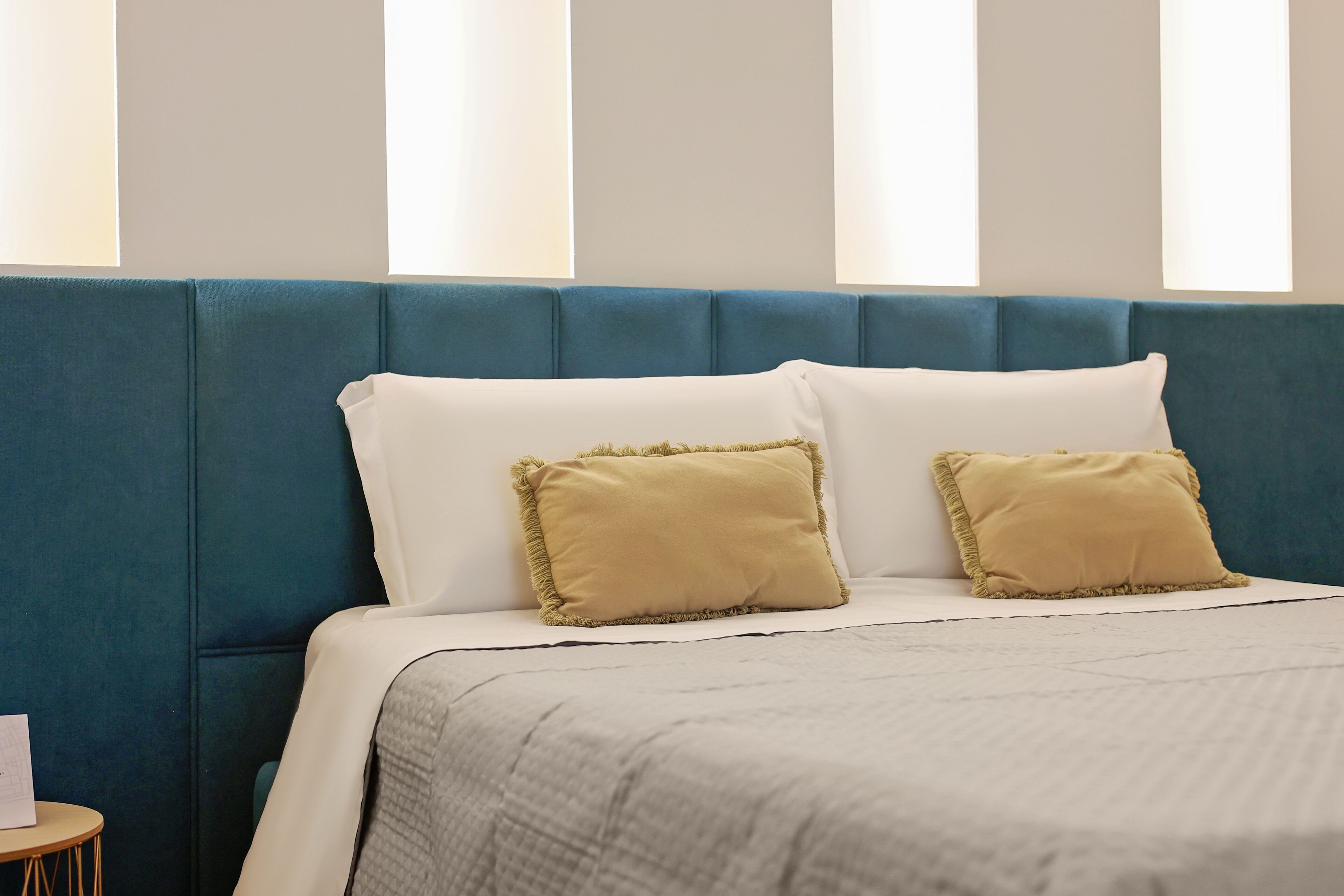 A bed with a blue headboard, two pillows, and a white bedspread.