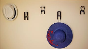 Un cappello bianco e un cappello blu con ricamato il marchio "Holiday Inn", entrambi appesi a ganci.
