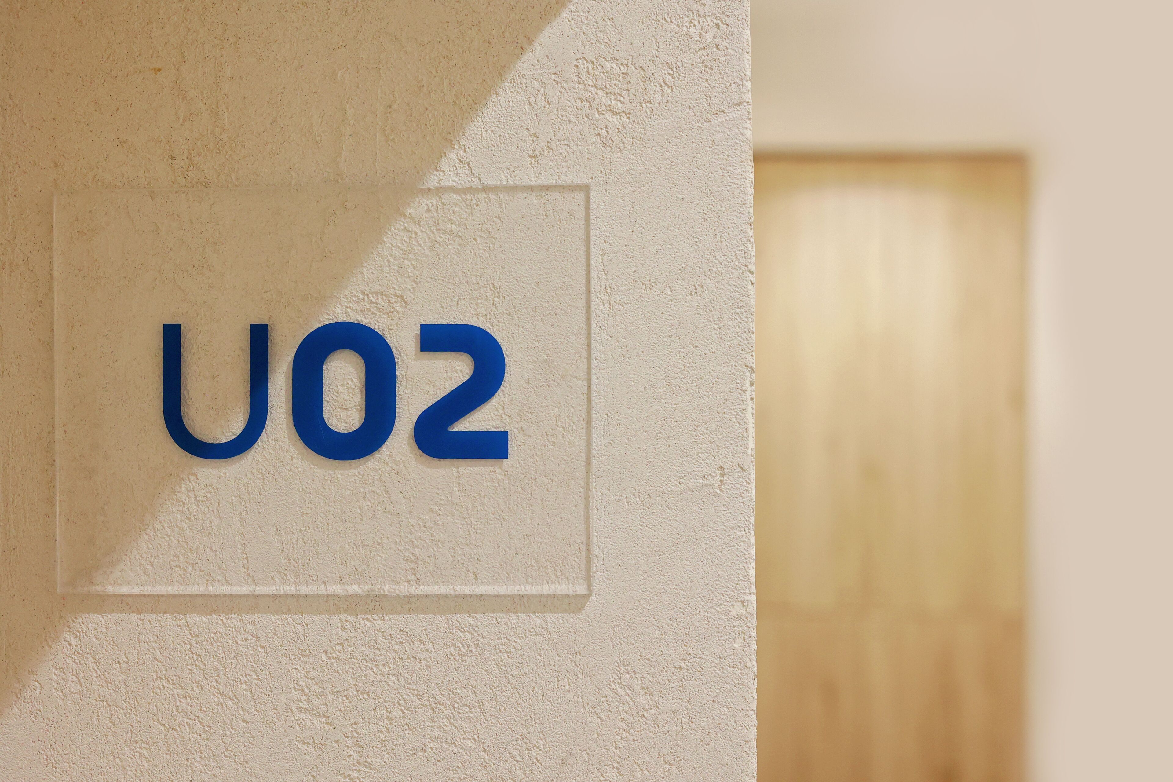 Un letrero con las letras "U02" en una pared con textura.